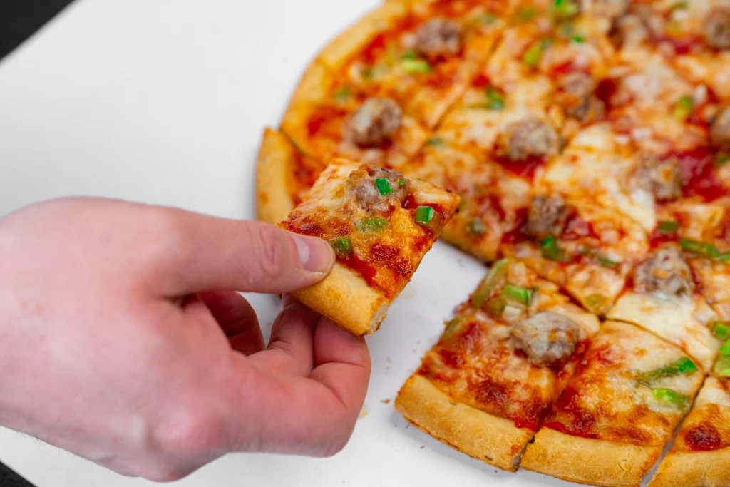 A hand picking up a slice of Sammy's pizza